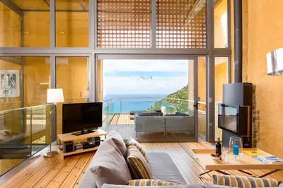 a living room with a couch and a large window at Beachfront Ravdoucha Epavlis Eleni Villa - Pool, Hot Tub, Gym, Sauna, Private Parking, WiFi in Chania Town