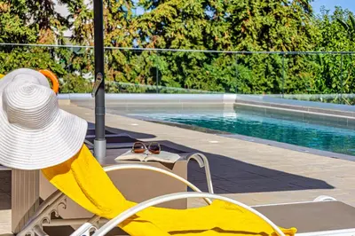 a hat and a chair next to a swimming pool at Chris villa with private ecologic pool and kid's playground! in Chania Town