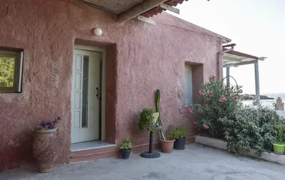 a pink house with potted plants in front of it at Seasound apartments in Galatás