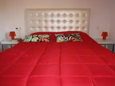 a red bed with a red comforter and pillows at Villa Pandora - Angela & Michali in Maleme