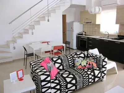 a living room with a black and white couch and a kitchen at Villa Pandora - Angela & Michali in Maleme