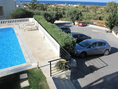 two cars parked in a parking lot next to a swimming pool at Villa Pandora - Angela & Michali in Maleme