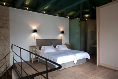 a bedroom with a bed with white sheets and a staircase at Athermigo Boutique Estate in Gavalochori