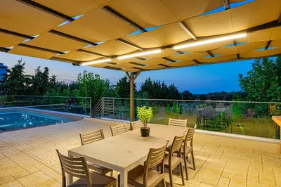 a patio with a table and chairs and a pool at Chris and Stratos villa with private ecologic pool and kid's playground! in Mourniaí