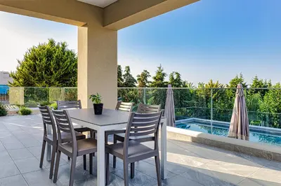 a table and chairs on a patio with a pool at Chris and Stratos villa with private ecologic pool and kid's playground! in Mourniaí
