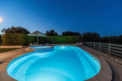 a large blue swimming pool with an umbrella at Villa Nimertis in Xirokámbion