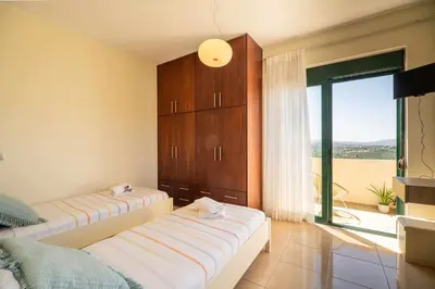 a bedroom with two beds and a large window at Villa Nimertis in Xirokámbion