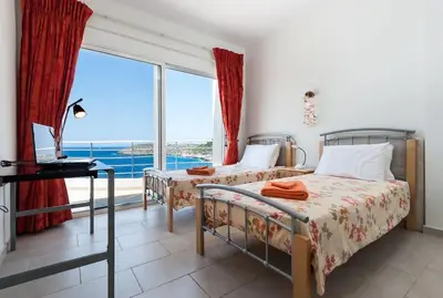 two beds in a room with a large window at Seascape in Tersanas