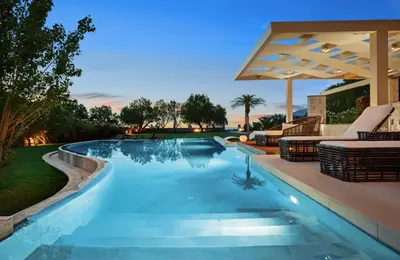 a swimming pool in a backyard with chairs and an umbrella at Villa Elvina in Kissamos