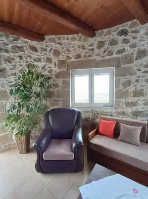 a leather chair and couch in a room with a stone wall at Rokka Pyrgos Amazing View - Maistros in Rókka
