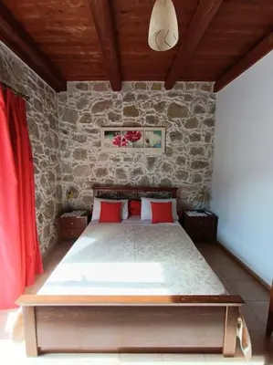 a bedroom with a bed in a stone wall at Rokka Pyrgos Amazing View - Maistros in Rókka