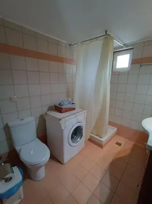 a bathroom with a toilet and a washing machine at Rokka Pyrgos Amazing View - Maistros in Rókka