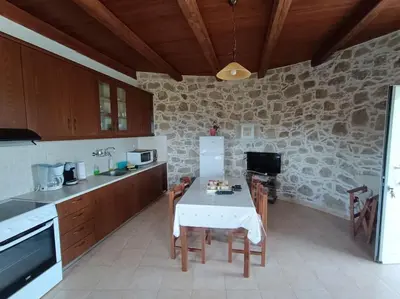 a kitchen with a table and a stone wall at Rokka Pyrgos Amazing View - Maistros in Rókka