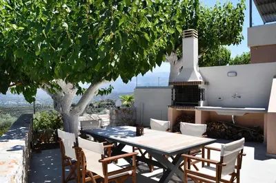 a table and chairs on a patio with a fireplace at Alexandras's Mansion - Fragkia's House in Ayiá