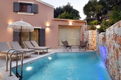 a pool with chairs and an umbrella next to a house at Alexandras's Mansion - Fragkia's House in Ayiá