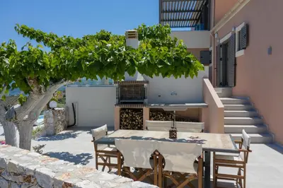 a table and chairs under a tree next to a building at Alexandras's Mansion - Fragkia's House in Ayiá