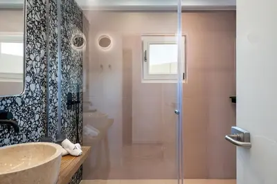 a bathroom with a glass shower and a sink at Domi Luxury Apartment by Cura Villas Collection in Chania Town