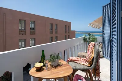 a balcony with two chairs and a table on a balcony at Domi Luxury Apartment by Cura Villas Collection in Chania Town