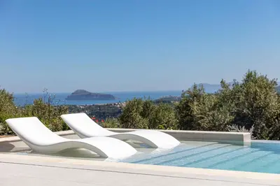 a pool with two white chairs sitting next to it at Villa Aglaea I Saltwater Pool & Amazing Seaview! in Chania Town