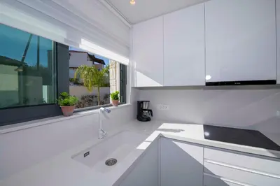 a white kitchen with a sink and a window at Kalyves Royal Villa I 