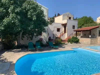 a pool with chairs and a house in the background at Carlas House, Kalyves in Tsivarás
