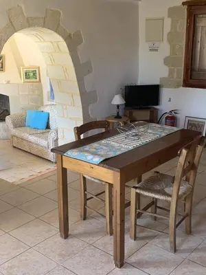 a wooden table with chairs and a living room at Carlas House, Kalyves in Tsivarás