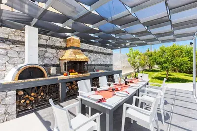 an outdoor dining area with a stone pizza oven at Villa Athena by Villa Plus in Almirida