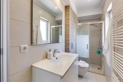 a white bathroom with a sink and a shower at Villa Athena by Villa Plus in Almirida