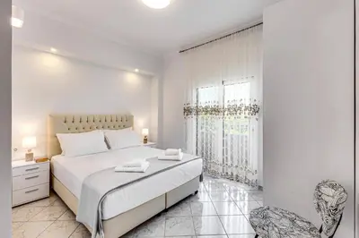 a white bedroom with a large bed and a window at Villa Athena by Villa Plus in Almirida
