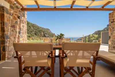 a dining room with a table and chairs and a view of the ocean at Aoria Villas in Palaiochóra