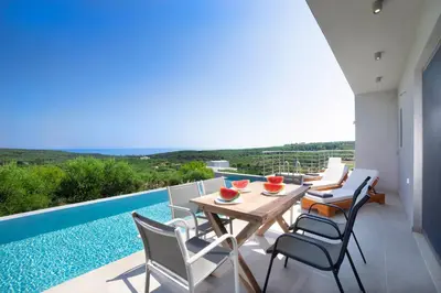 a patio with a table and chairs and a swimming pool at Villa Idyllic in Maleme