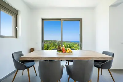 a dining room with a table and chairs and a window at Villa Idyllic in Maleme
