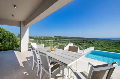 a dining room with a table and chairs and a swimming pool at Etheria Villa in Chania Town