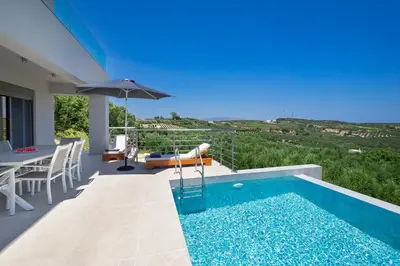 a villa with a swimming pool and a table and an umbrella at Etheria Villa in Chania Town