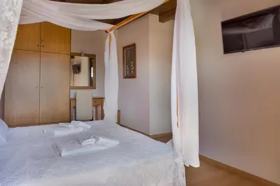 a bedroom with a bed with a white canopy at Villa Kois by PosarelliVillas in Tzitzifés