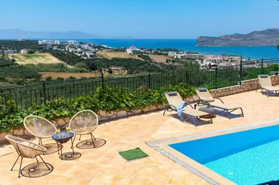 a patio with chairs and a swimming pool and the ocean at Pasiphae villas 1 & 2 in Stalos
