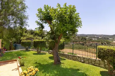 a garden with a tree and a fence at Pasiphae villas 1 & 2 in Stalos