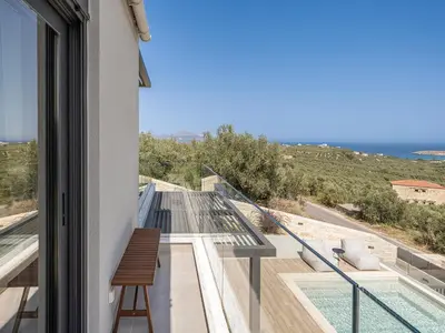 a house with a balcony with a view of the ocean at Melanthia Villas in Tsivarás