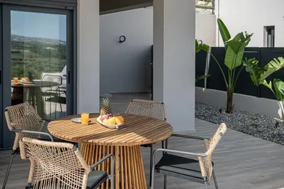 a wooden table with chairs and a bowl of fruit on a patio at Melanthia Villas in Tsivarás