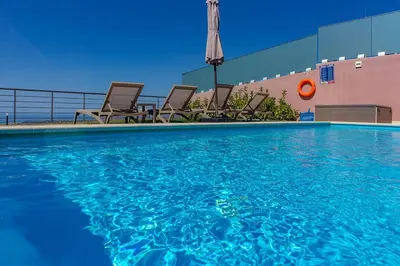a swimming pool with chairs and an umbrella at Apartment Lia with private eco pool - Amazing view in Chania Town