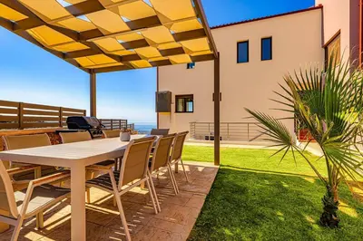 a table and chairs on a patio with a view of the ocean at Apartment Lia with private eco pool - Amazing view in Chania Town