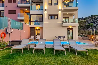 a building with chairs and a swimming pool at Apartment Lia with private eco pool - Amazing view in Chania Town