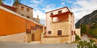 an orange building with a balcony next to a mountain at Villa Zourva in Zoúrva