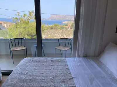 a bedroom with a bed and a large window with chairs at 2 sea view Villas as 1 by Chania Living Stories in Chania Town