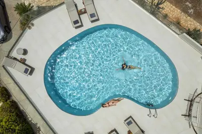 a person swimming in a large swimming pool at Seaview Villa Ormos, Heated Pool, Sea & Sun Villas in Chorafakia