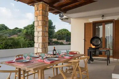 a wooden table and chairs on a patio with a fireplace at Seaview Villa Ormos, Heated Pool, Sea & Sun Villas in Chorafakia