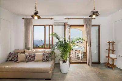 a living room with a couch and a large window at Seaview Villa Ormos, Heated Pool, Sea & Sun Villas in Chorafakia