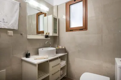 a bathroom with a sink and a toilet and a mirror at Seaview Villa Ormos, Heated Pool, Sea & Sun Villas in Chorafakia