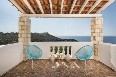 a patio with two chairs and a table and the ocean at Seafront Villa Shore, Sea & Sun Villas in Chorafakia