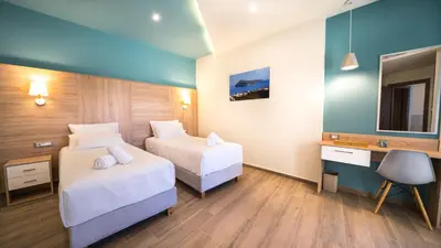 a hotel room with two beds and a desk and a mirror at Golden View Luxury Villa Platanias in Plataniás
